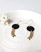 Boucles d’oreilles noir et doré en forme de rond, gros plan sur le design élégant