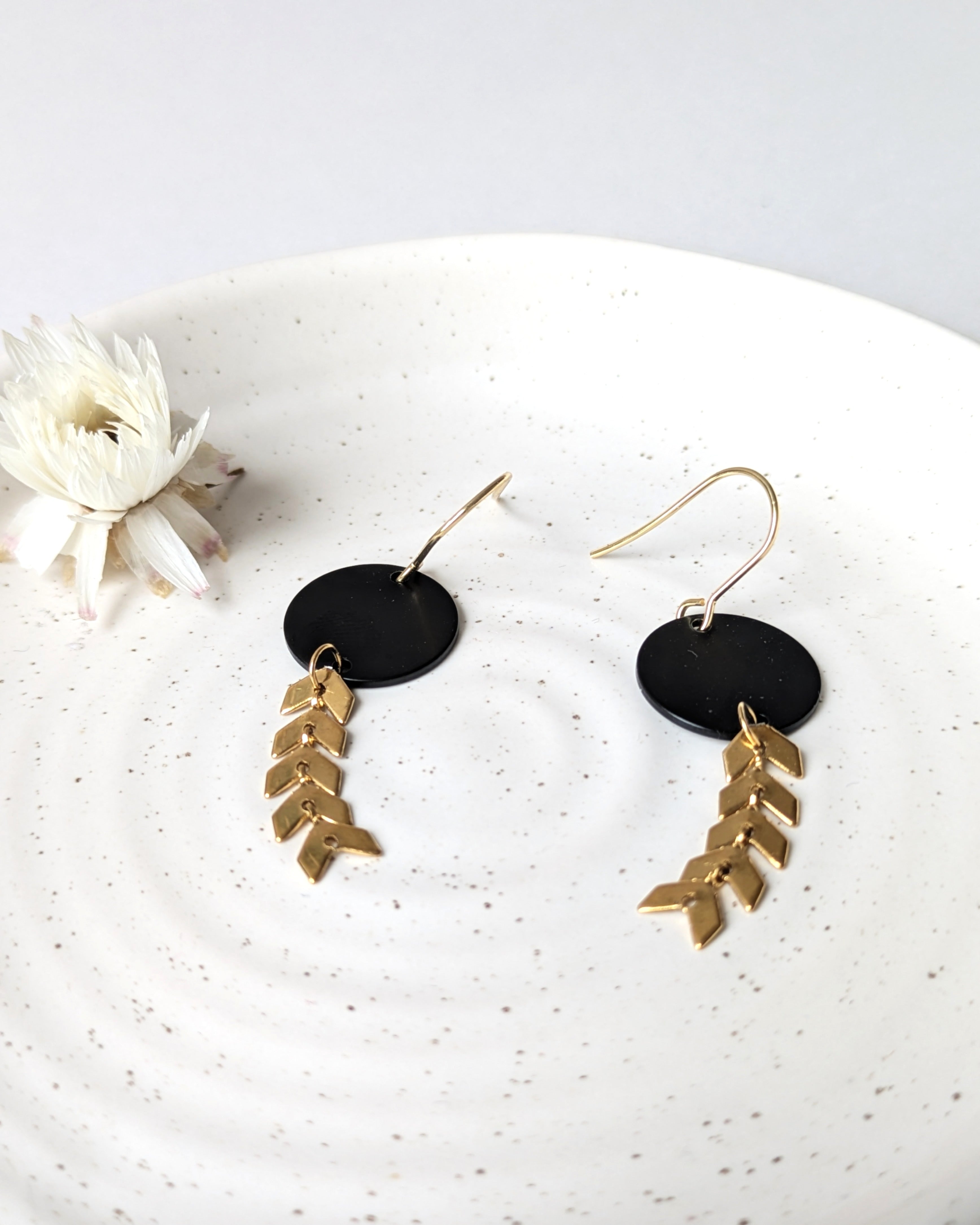 Boucles d’oreilles noir et doré en forme de rond, gros plan sur le design élégant