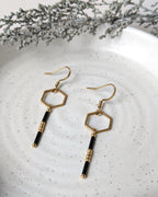 Boucles d’oreilles noir et doré au design hexagonal avec perles, gros plan sur les détails artisanaux