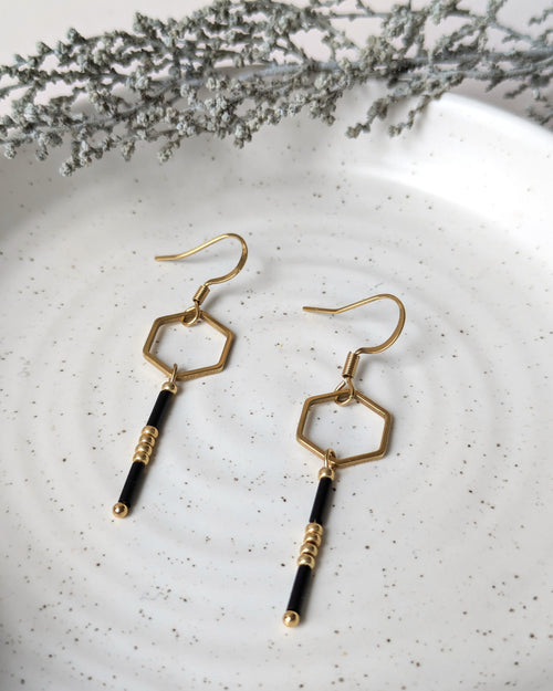 Boucles d’oreilles noir et doré au design hexagonal avec perles, gros plan sur les détails artisanaux