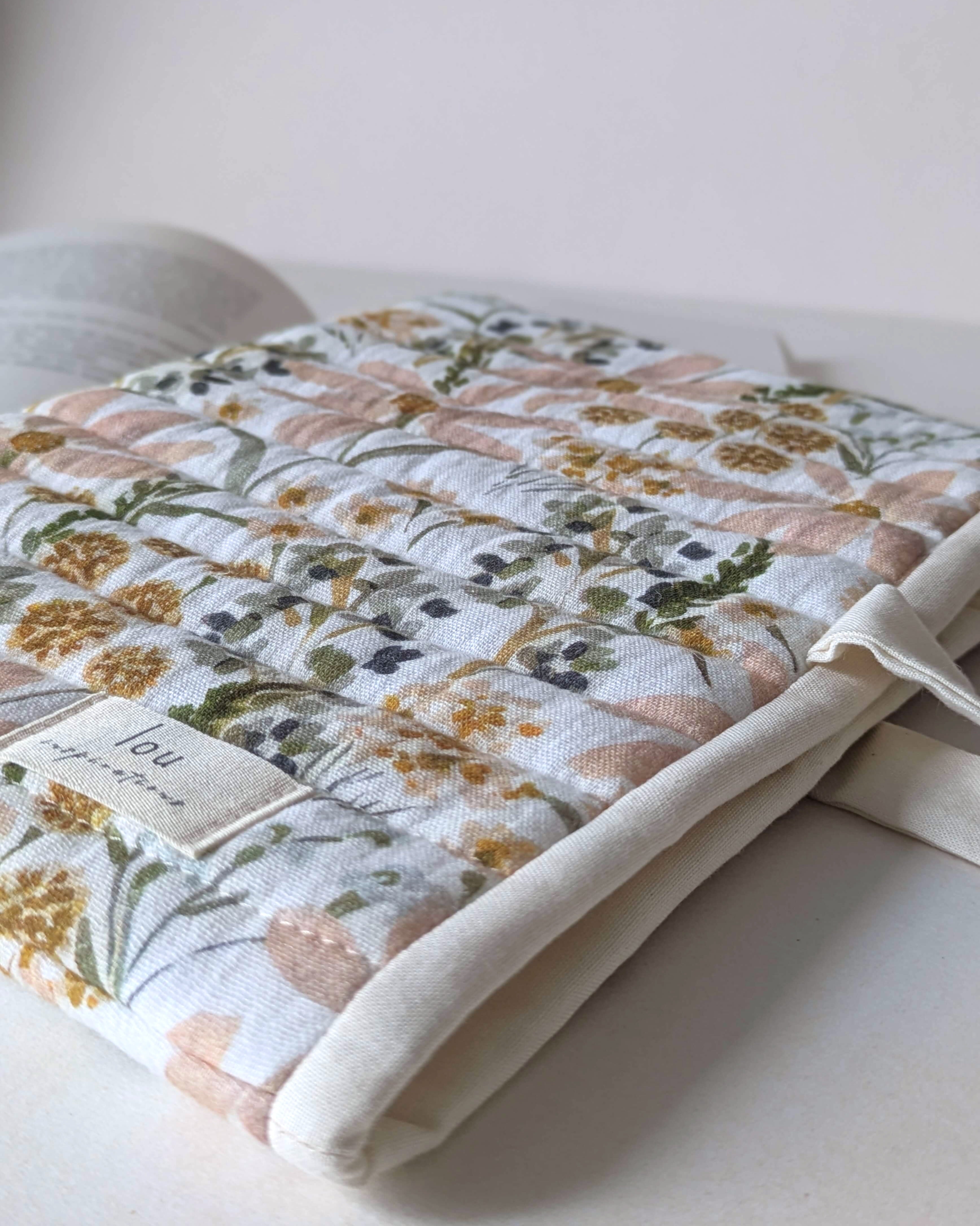 Détail du tissu floral aux teintes naturelles inspiré d'un champ de fleurs sauvages sur une pochette pour livre artisanale