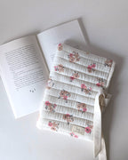 Pochette pour livre matelassée fleurie en gaze de coton écrue avec motif floral rose, confection artisanale pour protéger les romans et livres de poche.