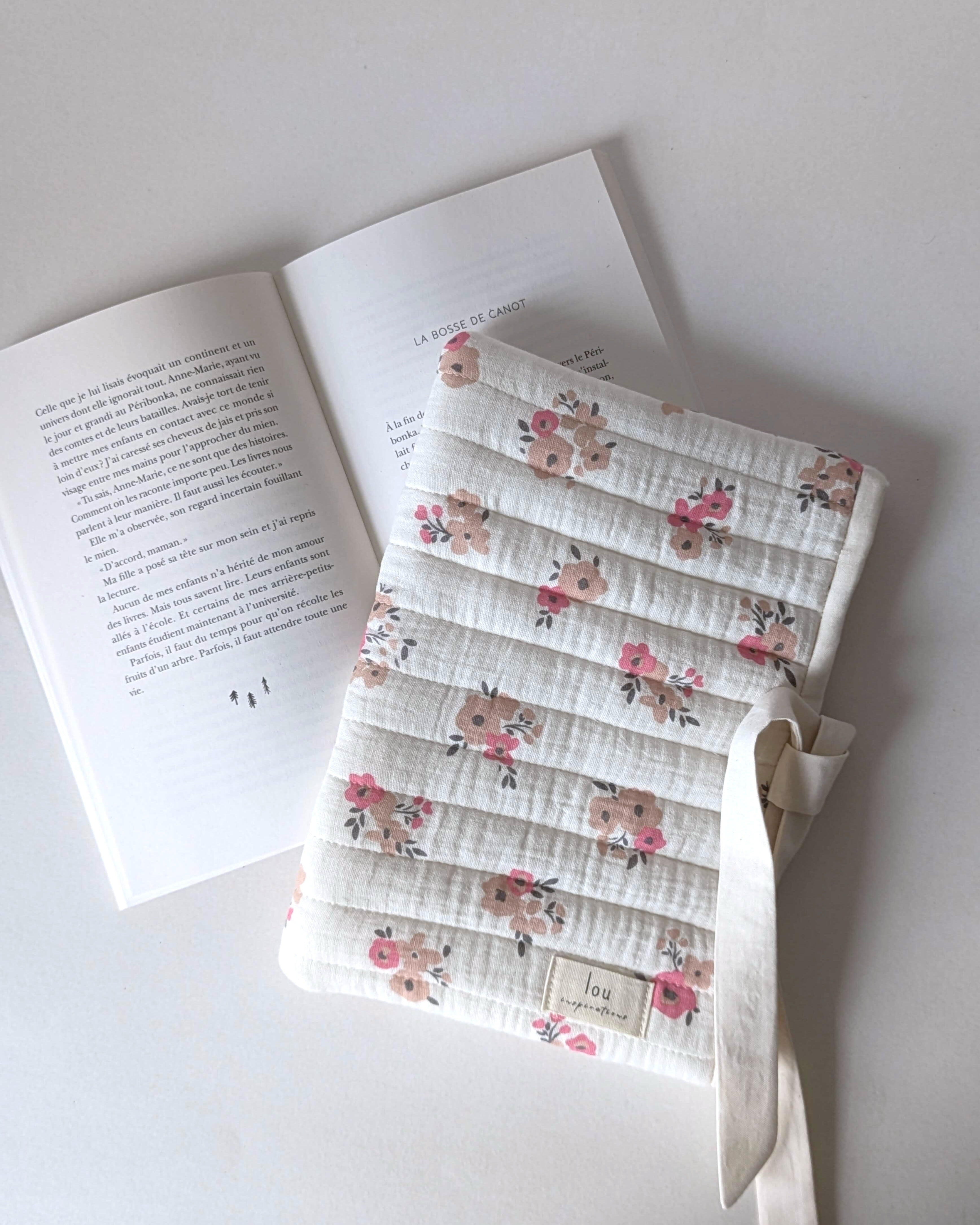 Pochette pour livre matelassée fleurie en gaze de coton écrue avec motif floral rose, confection artisanale pour protéger les romans et livres de poche.