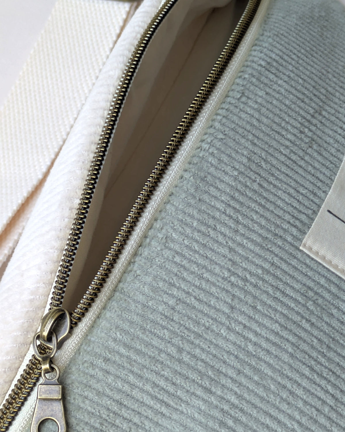 Intérieur doublé et fermeture éclair à dents bronze d’un sac banane en velours côtelé tricolore