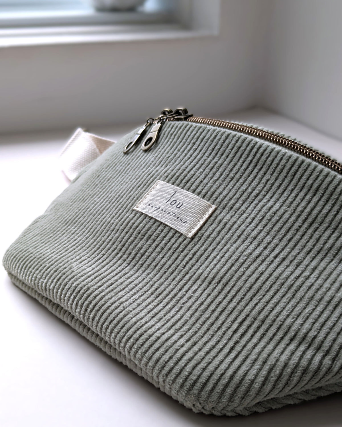 Texture du velours côtelé bio sauge et double tirette bronze d’un sac banane fait main Lou Inspirations