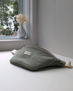 Sac banane en velours côtelé bio sauge près d’un vase de fleurs séchées avec la lumière naturelle de la fenêtre