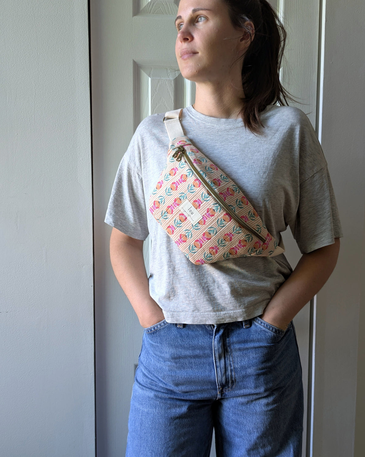 Femme portant un sac banane en coton matelassé à motif fleuri et coloré en bandoulière 
