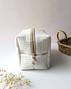 Trousse en tissu gaufré beige, création artisanale compacte avec zip doré résistant, pensée pour le quotidien